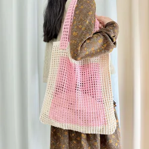 Detailansicht der rosa und beigen Häkel-Tasche mit Lochmuster, ideal für den Strand.
