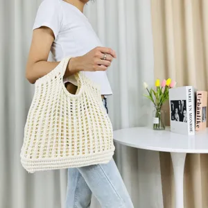 Gros plan détaillé d'un sac cabas creux en tricot tissé beige dans un décor intérieur.