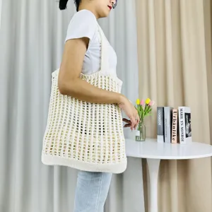 Detailansicht einer eleganten beige gestrickten Schulter-Tragetasche mit Dekoration.