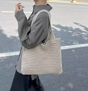 Vista dettagliata di una borsa a tracolla in maglia beige indossata in una scena casual quotidiana.