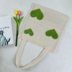 Nahaufnahme der Strick-Tasche mit grünen Plüschherzen und feinen Perlenbesatz-Details.