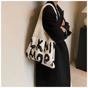 Detailaufnahme einer stilvollen schwarz-weißen Strick-Tasche mit gewebten Buchstaben am Modell.