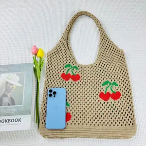 Detalle del bolso de punto con textura de malla y bonito diseño de cerezas bordadas.