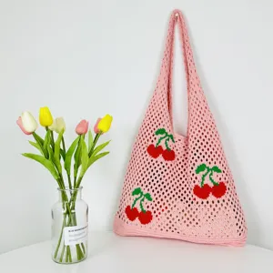 Detalle de bolso tote de punto rosa con bonitos patrones de cerezas rojas y diseño.