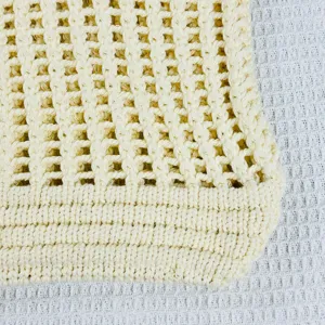 Gros plan du sac cabas en maille beige montrant une texture crochetée et un design creux.