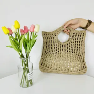 Vue détaillée du sac cabas ajouré tissé beige mettant en valeur sa texture et sa poignée.