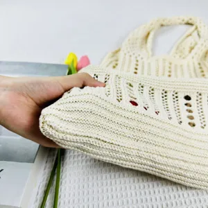 Nahaufnahme der Textur einer beigen gestrickten Schultertasche, ideal für Strand und Sommer.