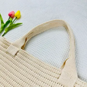 Dettaglio manico borsa tote in maglia beige, design primo piano borsa intrecciata casual.