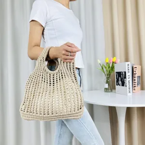 Vue détaillée du sac cabas ajouré en tricot beige porté par le modèle, style plage décontracté.