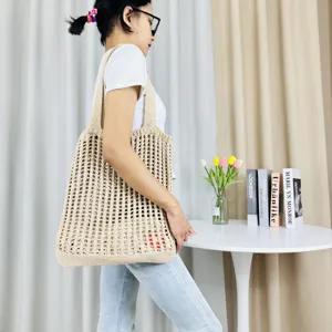 Detailaufnahme einer beigen, hohlen Strick-Tasche auf der Schulter, lässige Sommer-Strandtasche.