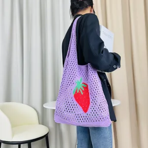 Detailansicht der lila gestrickten Tasche mit rotem Erdbeermuster in einem schönen Raum.