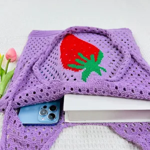 Detailansicht einer stilvollen lila geflochtenen Tasche mit süßem rotem Erdbeermuster.