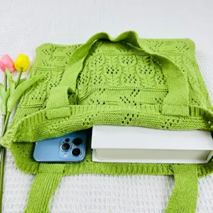 Nahaufnahme der grünen Strick-Häkel-Tasche mit Frühlings-Tulpen und Handy-Requisite im Detail.