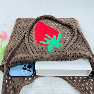 Detailaufnahme der braunen gestrickten Lochmuster-Tasche mit rotem Erdbeer-Muster.