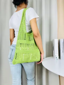Detailansicht der stilvollen grünen Häkel-Umhängetasche mit Lochmuster, getragen von einem Model.