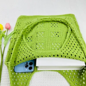 Detailansicht der grüne geflochtene Hohl-Strick-Schultertasche, zeigt Kapazität mit Buch.