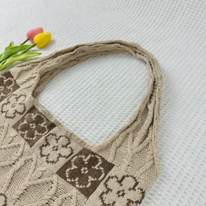 Detailed view of women knitted tote bag with chic floral pattern beige brown knit fabric design.