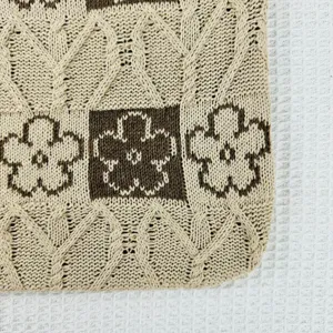 Close-up detail of knitted tote bag featuring cable knit and brown flower jacquard pattern.