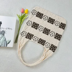 Knitted tote bag detail showing brown and white floral pattern and textured fabric surface.