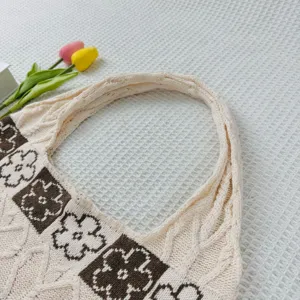 Detailed shot of a chic beige knitted tote bag featuring stylish brown square flower patterns.