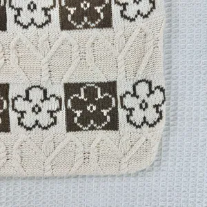 Knit tote bag detail, brown and white floral pattern with cozy cable knit texture for women.