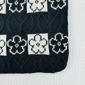 Black and white knitted floral tote bag detail close-up showing texture and pattern design.