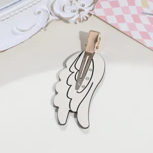 Detail view of a sweet angel wing duckbill hair clip with rhinestones and white enamel finish.