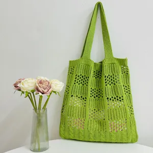 Detailaufnahme einer grünen Stricktasche, die feine Maschenmuster und die langen Henkel zeigt.