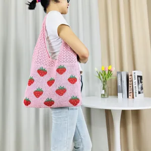 Gedetailleerd uitzicht op de schattige roze gebreide shopper met aardbeienmotief.
