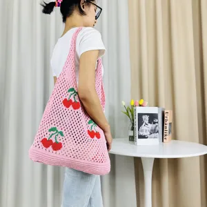 Primer plano detallado del bolso tote de ganchillo rosa con bonitos patrones de cerezas.