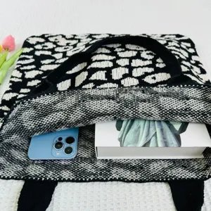 Strick Tragetasche Innendetail, schwarz-weisses Muster mit Smartphone und grossem Buch.