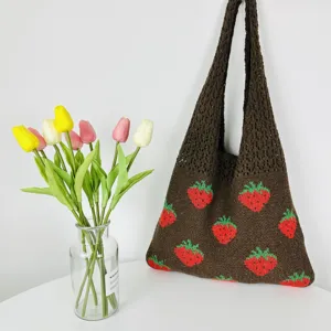 Bruine gebreide aardbei tote tas detail met schattig patroon en zachte stof textuur.