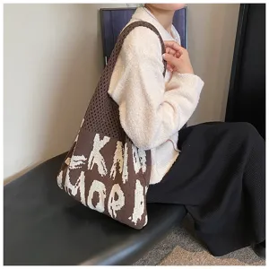 Detailansicht der braunen Stricktasche mit kontrastierendem weißem Buchstabenmuster am Modell.
