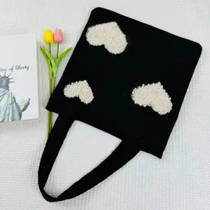 Schwarze Strick-Tragetasche mit weißen flauschigen Herzmustern, lässige Handtasche für den Alltag.