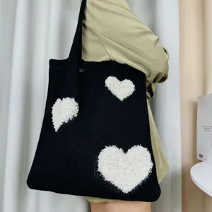 Detailansicht der schwarzen Strick-Tasche mit flauschigen weißen Herz-Mustern und Textur.