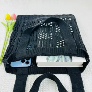 Detailansicht der schwarzen Strick-Tote-Bag mit Netzmuster, Staufach und Accessoires.
