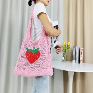 Detailansicht einer rosa Strick-Tragetasche mit rotem Erdbeermuster für den täglichen Gebrauch.