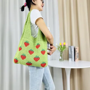 Gedetailleerd overzicht van groen gebreide tote bag met aardbeienmotief, levensstijlscène.