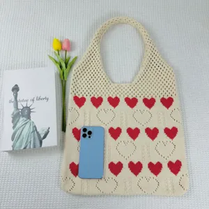Nahaufnahme Detail der Stricktasche mit rotem Herzmuster und hohlem Strickmuster.