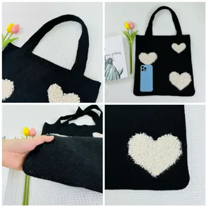 Schwarze Stricktasche Detail mit strukturierten weißen flauschigen Herzen und Trageriemen.
