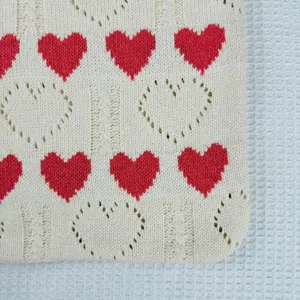 Nahaufnahme Detail der Stricktasche mit rotem Herzmuster und Lochmuster, weicher Stoff.