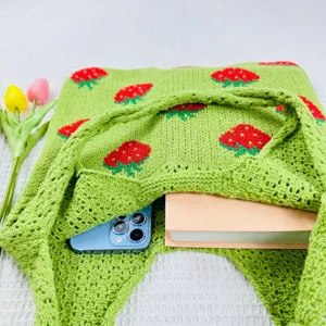 Gedetailleerd overzicht van groen aardbei gebreide shopper tas met grote binnenste capaciteit.