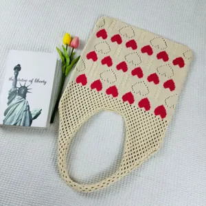 Detailaufnahme der beigen gestrickten Tasche mit roten Herzen und feinem Netzmuster.