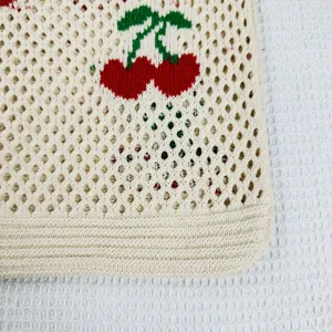 Detalle de cerca del bolso tejido con lindo patrón de cereza y textura calada.