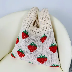 Close-up van de schattige aardbei gebreide tas, met details van het rode fruitpatroon.