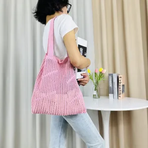 Detailed view of a pink knit hollow shoulder tote bag, casual beach style daily use.