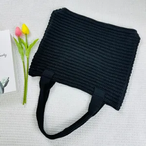 Vista dettagliata della borsa shopper nera in maglia con trama tessuta e doppi manici.