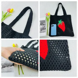 Detailaufnahme der schwarzen Stricktasche mit Lochmuster und rotem Erdbeer-Muster Design.