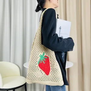 Beige gestrickte Netztasche mit rotem Erdbeermuster fuer laessigen Strand und Alltag.