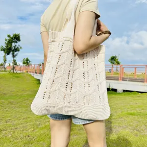 Dettaglio della borsa a spalla in maglia beige traforata che mostra la trama intrecciata e capiente.